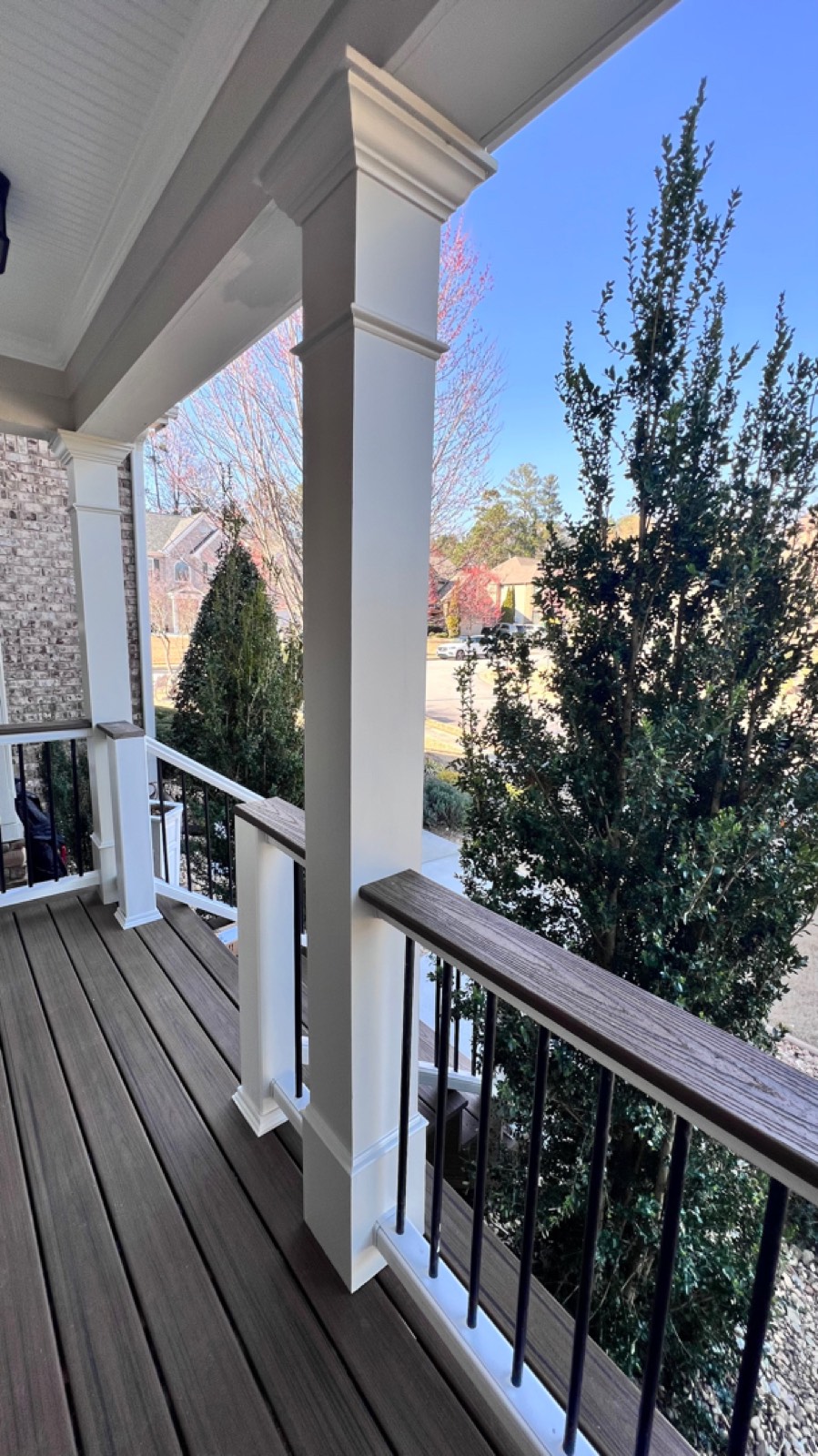 Finished porch &mdash; wrapped columns, Trex Transcend railing, and a Havana Gold cocktail rail