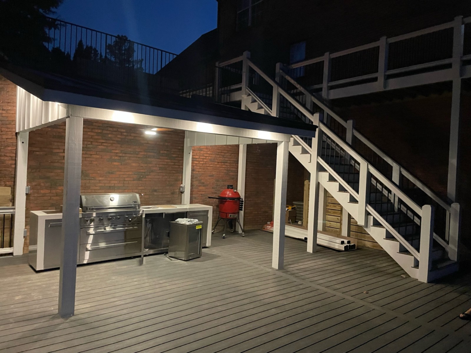 The finished outdoor kitchen under its new pitched roof, lit by recessed soffit lighting